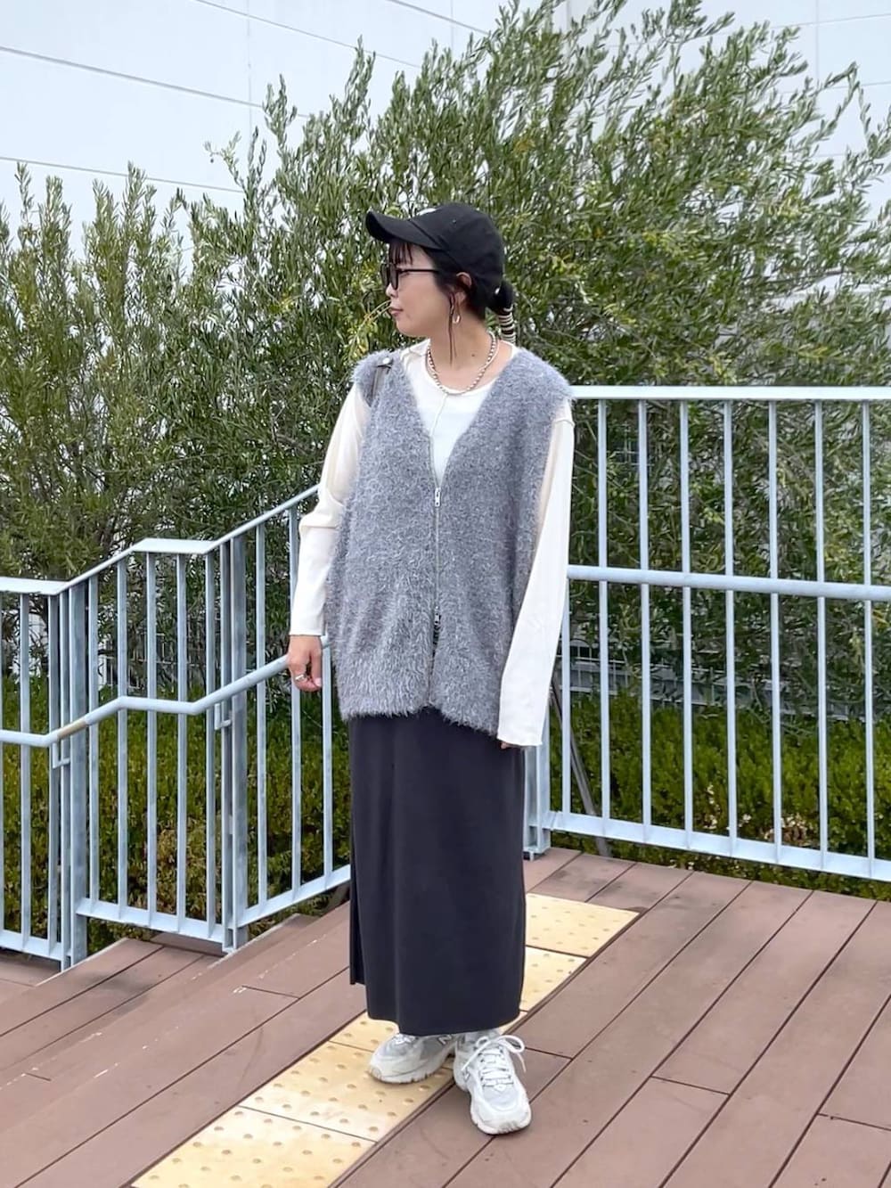 グレー系のスカート、グレー系のベスト、ホワイト系のTシャツ/カットソーを着用したレディースの秋コーディネートの2枚目の写真