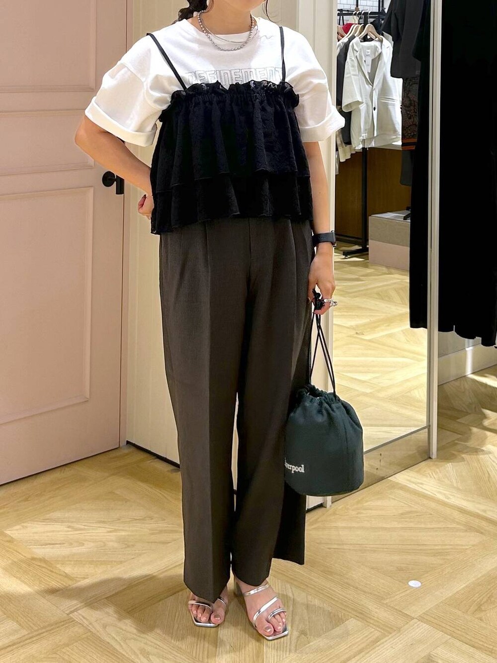 グレー系のスラックス、シルバー系のサンダル、ホワイト系のTシャツ/カットソーを着用したレディースの夏コーディネートの2枚目の写真
