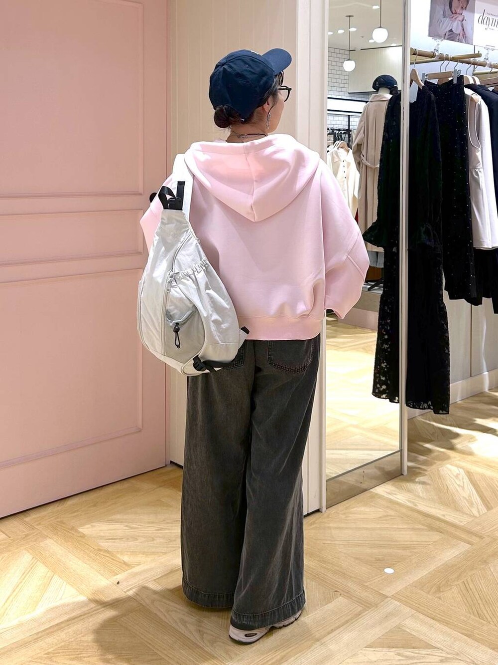 ピンク系のパーカー、ブラック系のデニムパンツ、グレー系のタンクトップを着用したレディースの春コーディネートの4枚目の写真