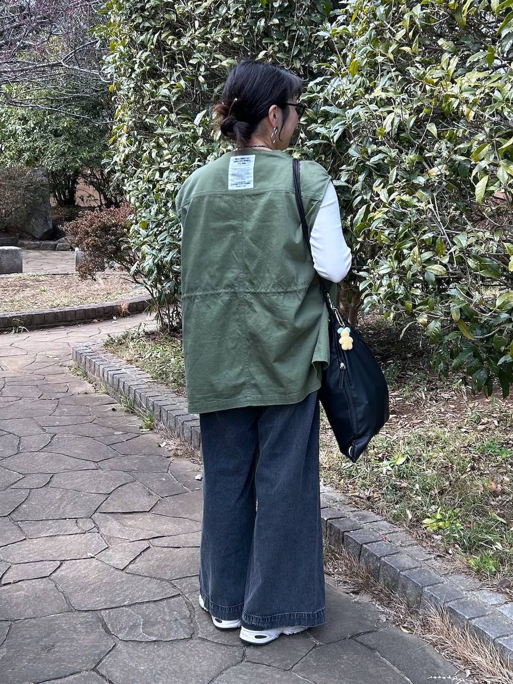 ブラック系のデニムパンツ、ホワイト系のTシャツ/カットソー、ブラック系のベストを着用したレディースの冬コーディネートの4枚目の写真