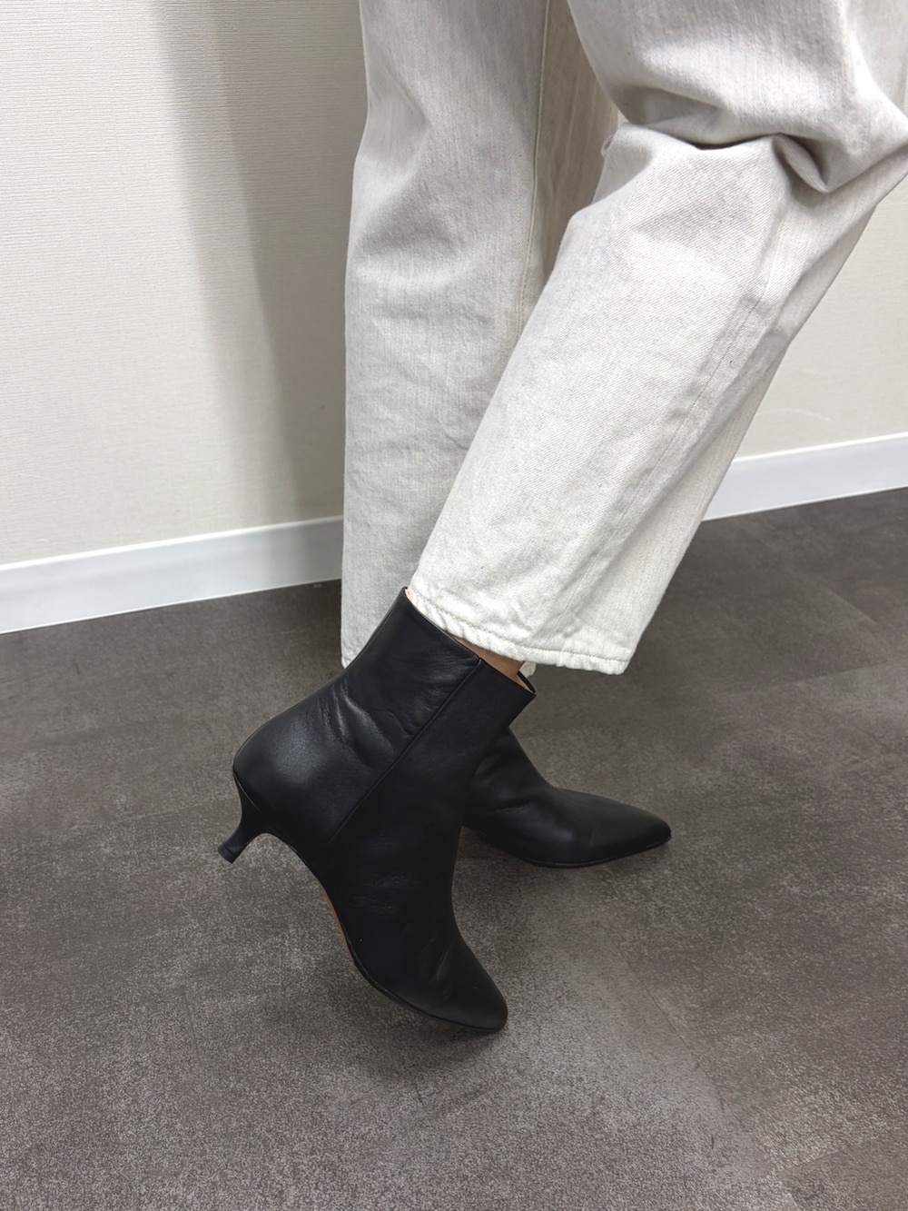 ブラック系のハンドバッグ、ブラック系のブーツ、グレー系のカーディガン/ボレロを着用したレディースの秋コーディネートの4枚目の写真