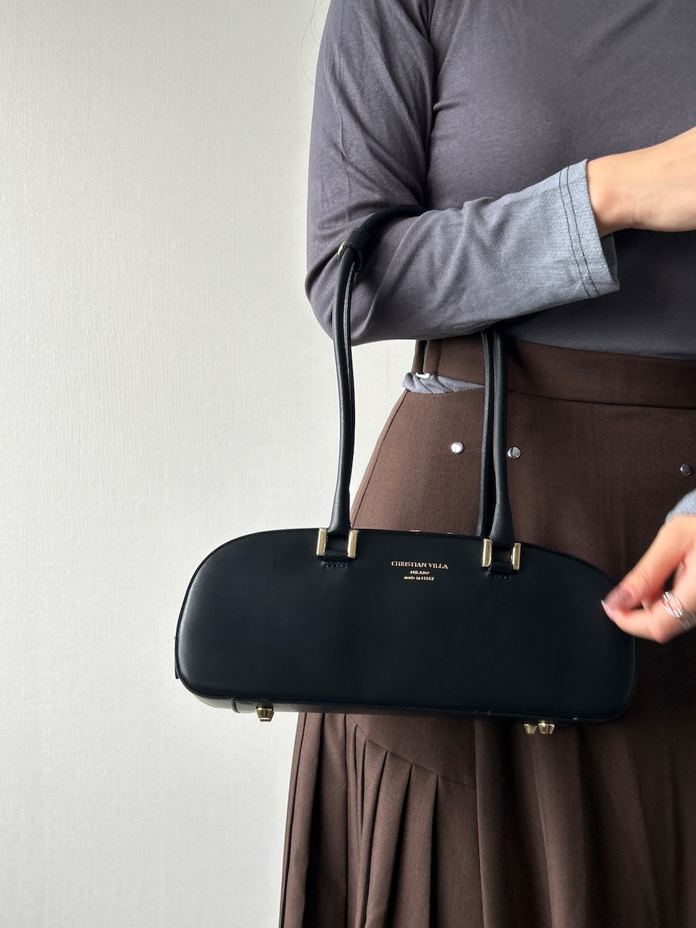 ブラウン系のスカート、ブラウン系のローファー、レッド系のショルダーバッグを着用したレディースの秋コーディネートの3枚目の写真