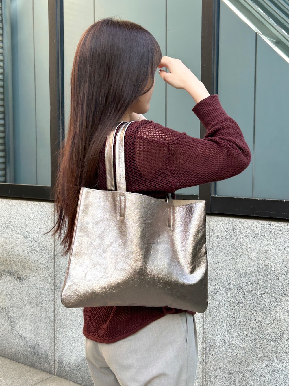 ベージュ系のパンツ、ブラウン系のニット/セーター、その他のトートバッグを着用したレディースの夏コーディネートの3枚目の写真