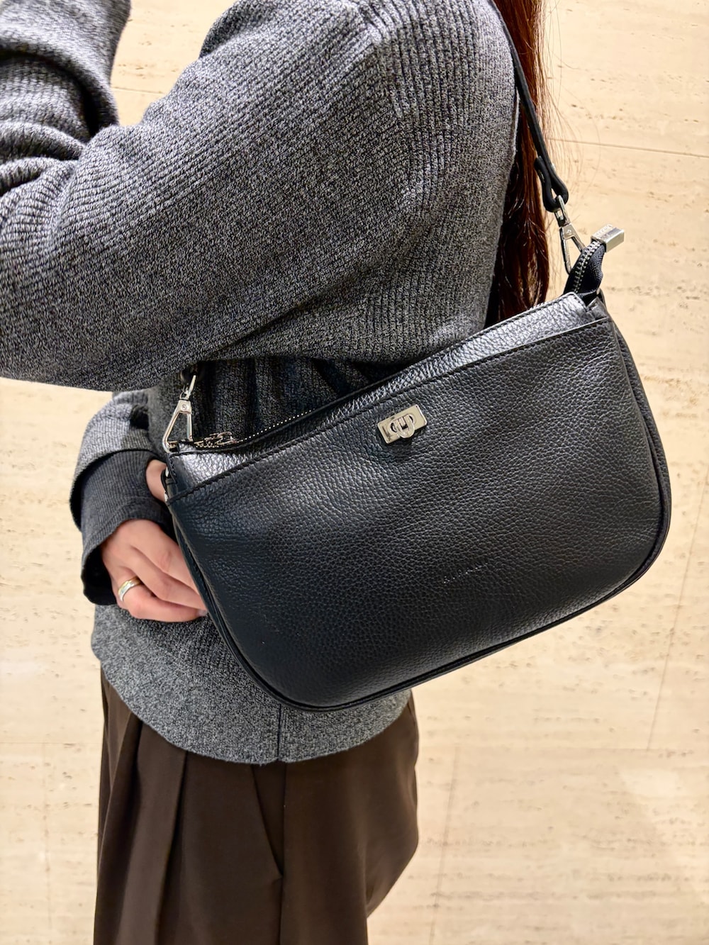 ブラック系のハンドバッグ、ブラック系のスニーカー、ブラウン系のダウンベストを着用したレディースの冬コーディネートの2枚目の写真