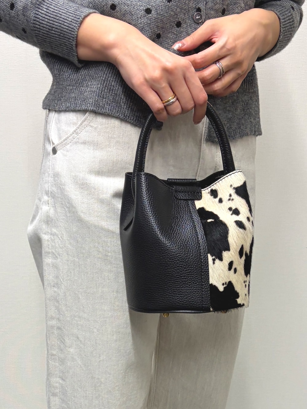 ブラック系のハンドバッグ、ブラック系のブーツ、グレー系のカーディガン/ボレロを着用したレディースの秋コーディネートの3枚目の写真