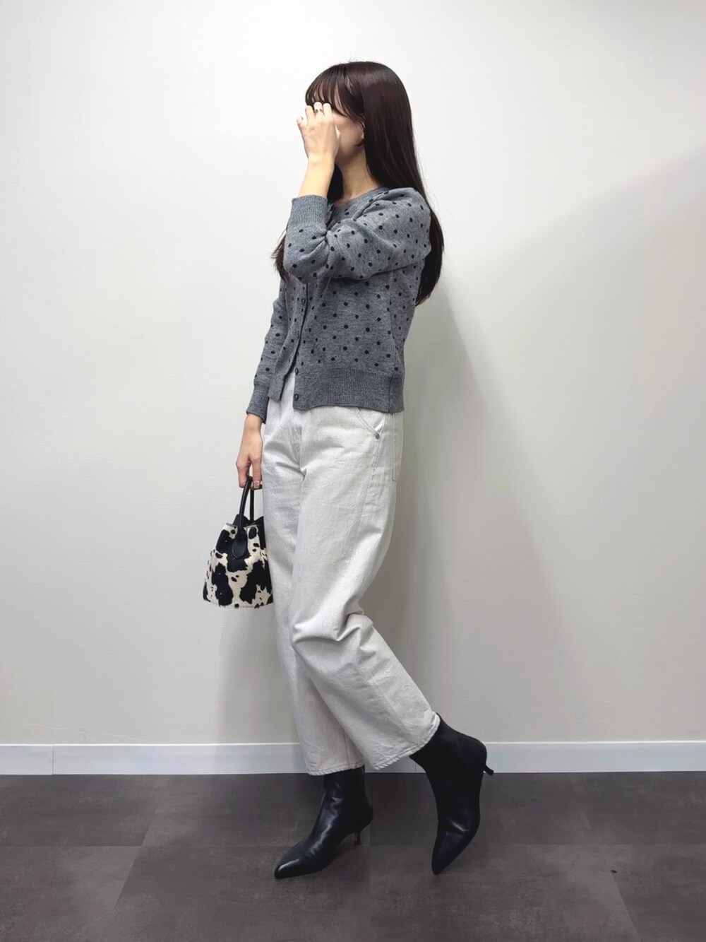 ブラック系のハンドバッグ、ブラック系のブーツ、グレー系のカーディガン/ボレロを着用したレディースの秋コーディネートの2枚目の写真