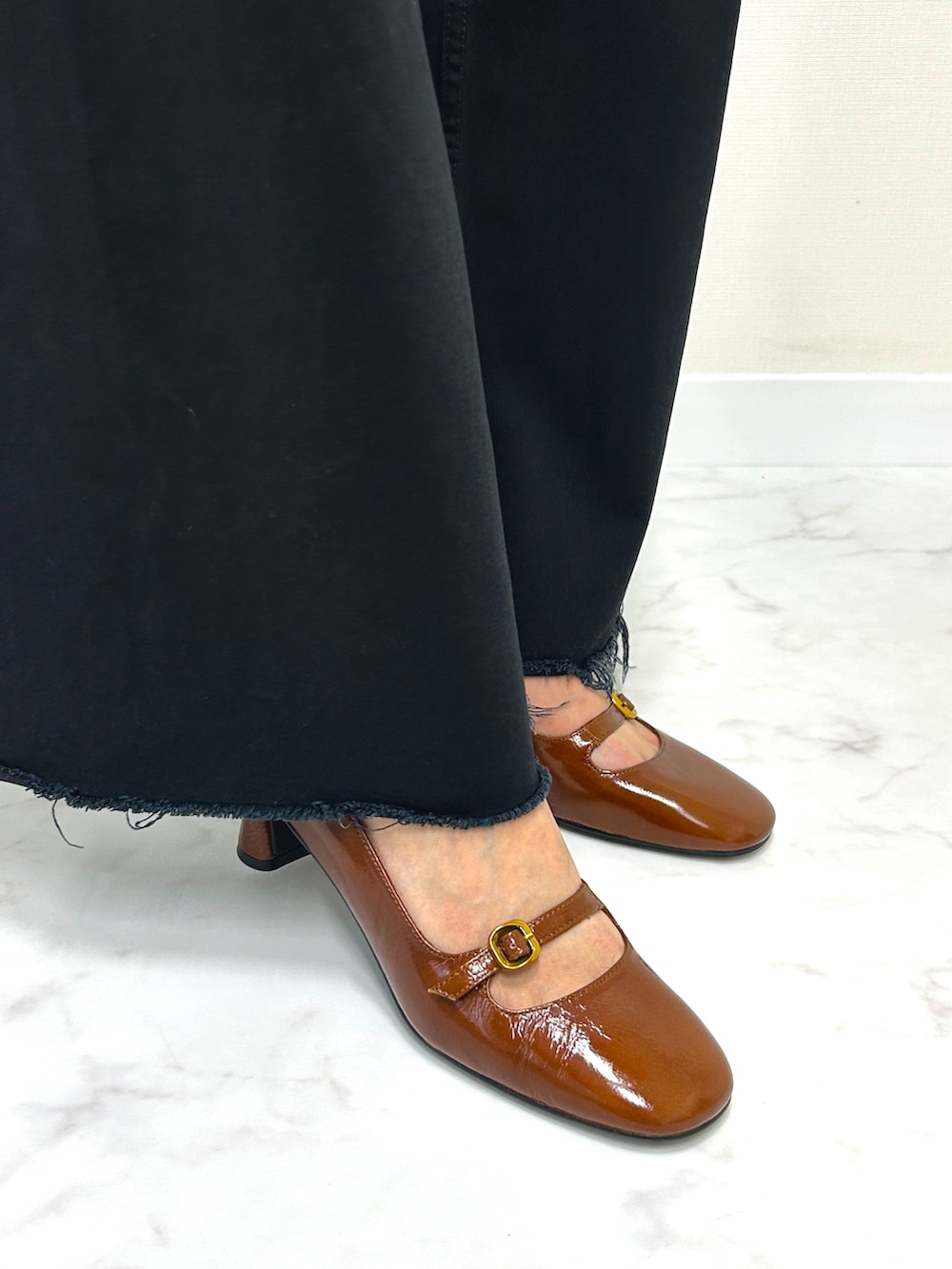 ブラウン系のパンプス、ブラック系のパンツ、ホワイト系のカーディガン/ボレロを着用したレディースの秋コーディネートの2枚目の写真