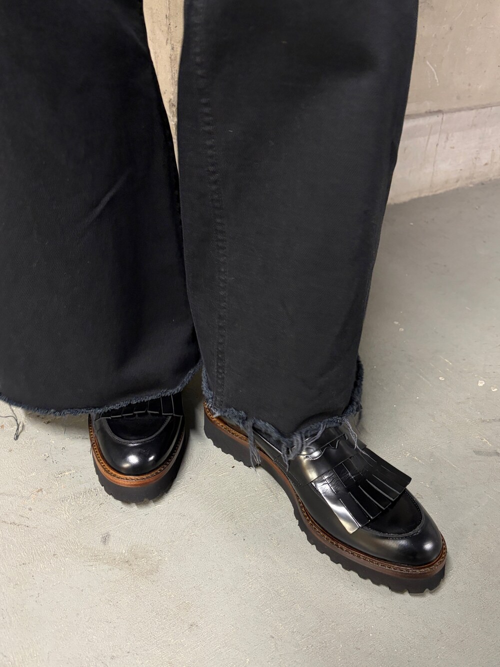 ブラック系のパンツ、ブラック系のローファー、ブラック系のショルダーバッグを着用したレディースの冬コーディネートの2枚目の写真