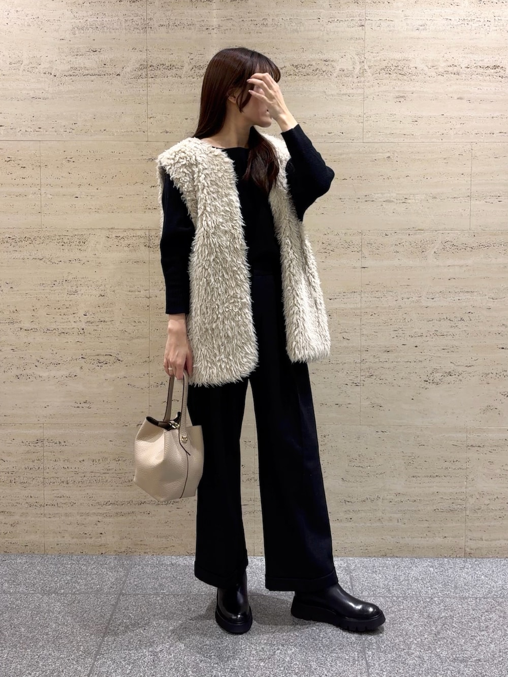 ブラック系のニット/セーター、ベージュ系のハンドバッグ、ブラック系のブーツを着用したレディースの冬コーディネートの2枚目の写真