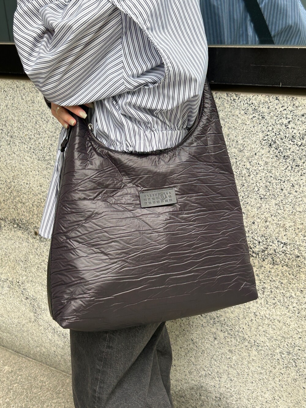 ブラック系のショルダーバッグ、グレー系のスニーカー、ブルー系のTシャツ/カットソーを着用したレディースの春コーディネートの3枚目の写真