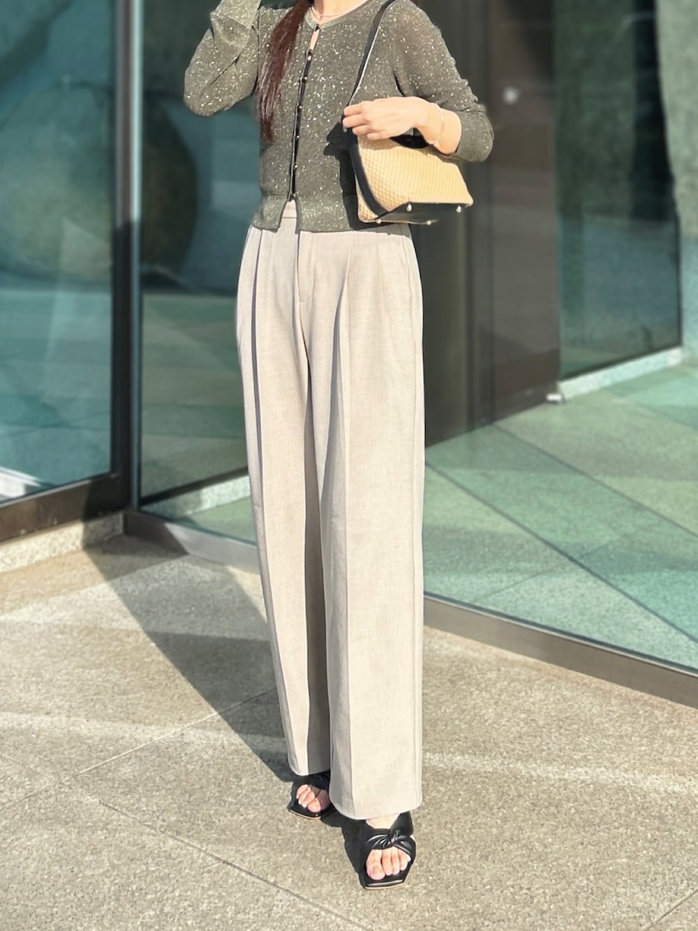 ベージュ系のスラックス、ブラック系のショルダーバッグ、ブラック系のサンダルを着用したレディースの夏コーディネートの2枚目の写真