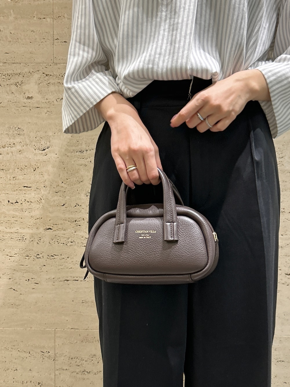 ブラウン系のハンドバッグ、ブラック系のパンプス、ホワイト系のシャツ/ブラウスを着用したレディースの秋コーディネートの2枚目の写真