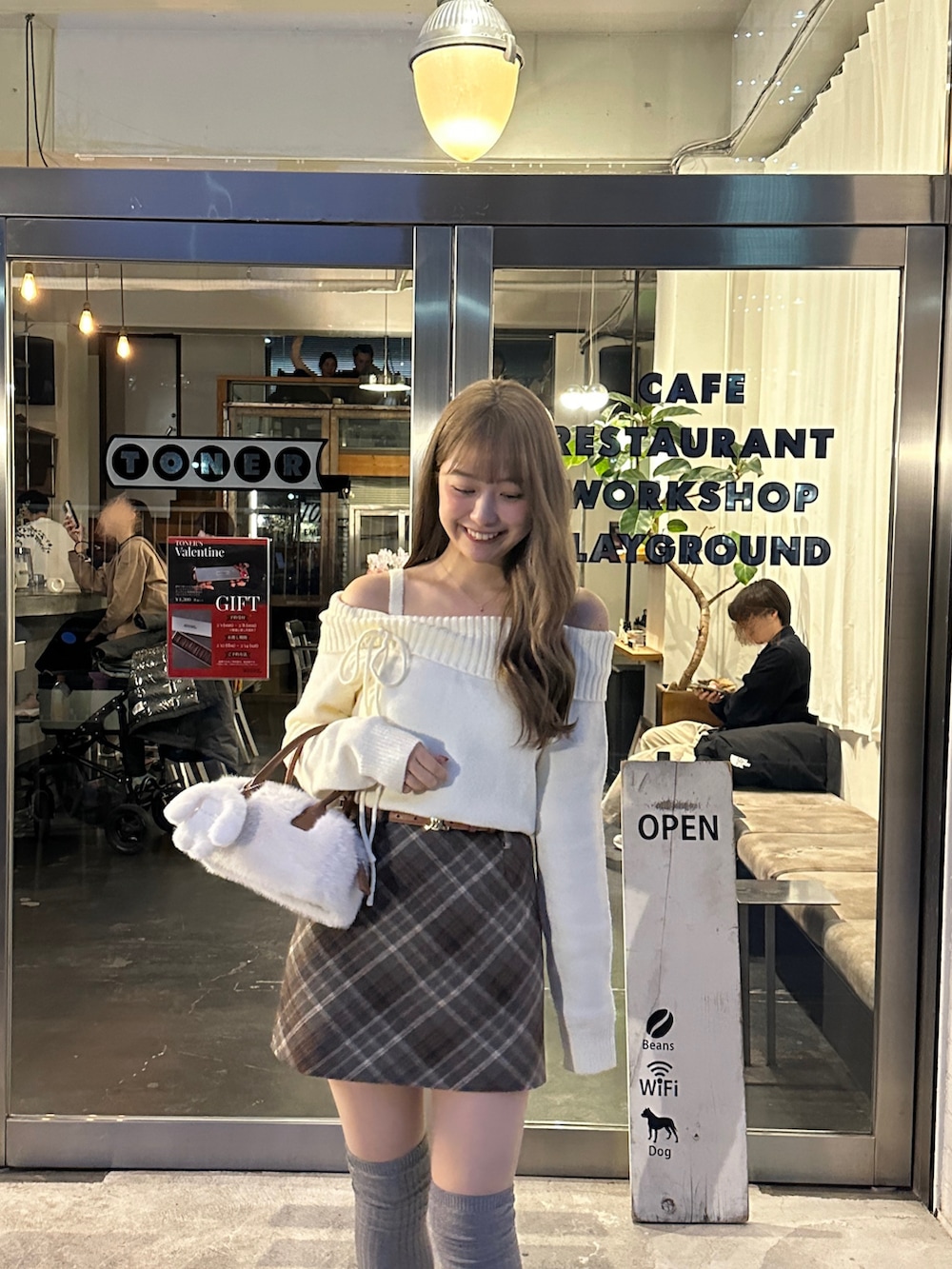 ホワイト系のニット/セーター、ホワイト系のショルダーバッグ、ブラウン系のスカートを着用したレディースの冬コーディネートの2枚目の写真