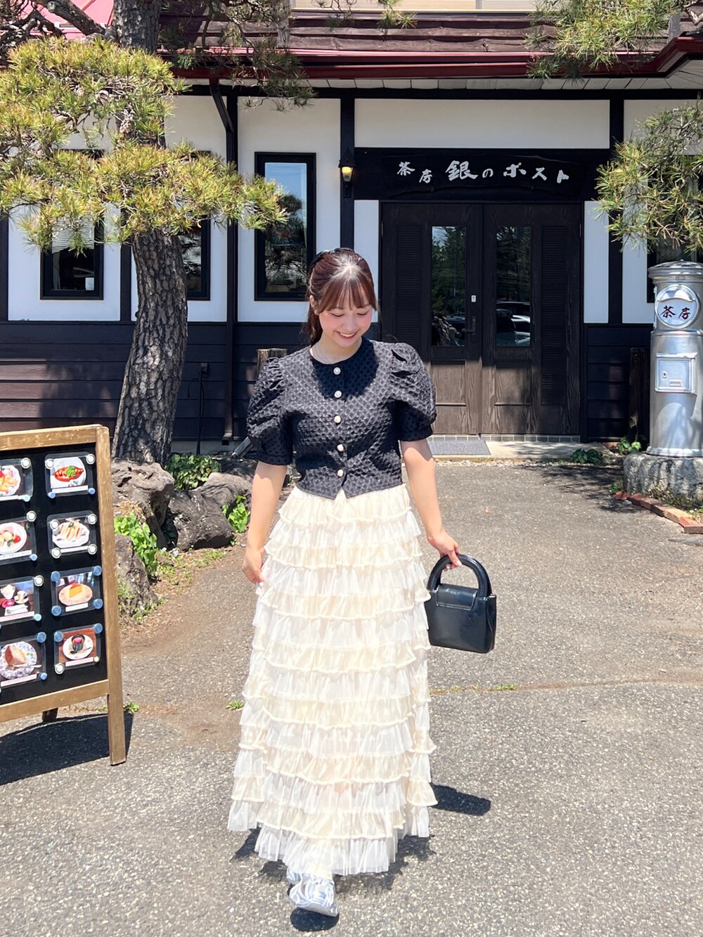 ブラック系のトップス、ホワイト系のスカート、シルバー系のスカートを着用したレディースの夏コーディネートの3枚目の写真