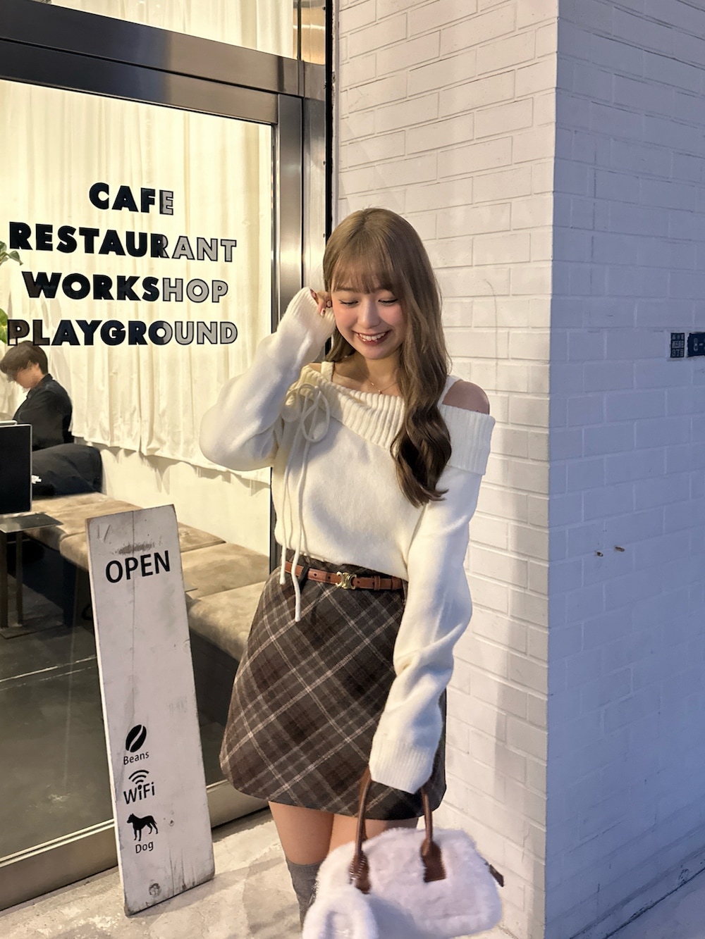 ホワイト系のニット/セーター、ホワイト系のショルダーバッグ、ブラウン系のスカートを着用したレディースの冬コーディネートの4枚目の写真