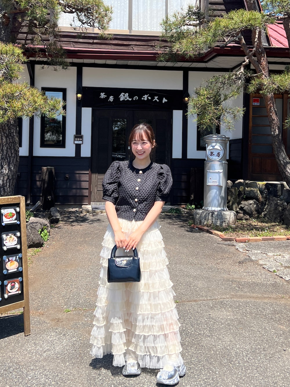 ブラック系のトップス、ホワイト系のスカート、シルバー系のスカートを着用したレディースの夏コーディネートの2枚目の写真