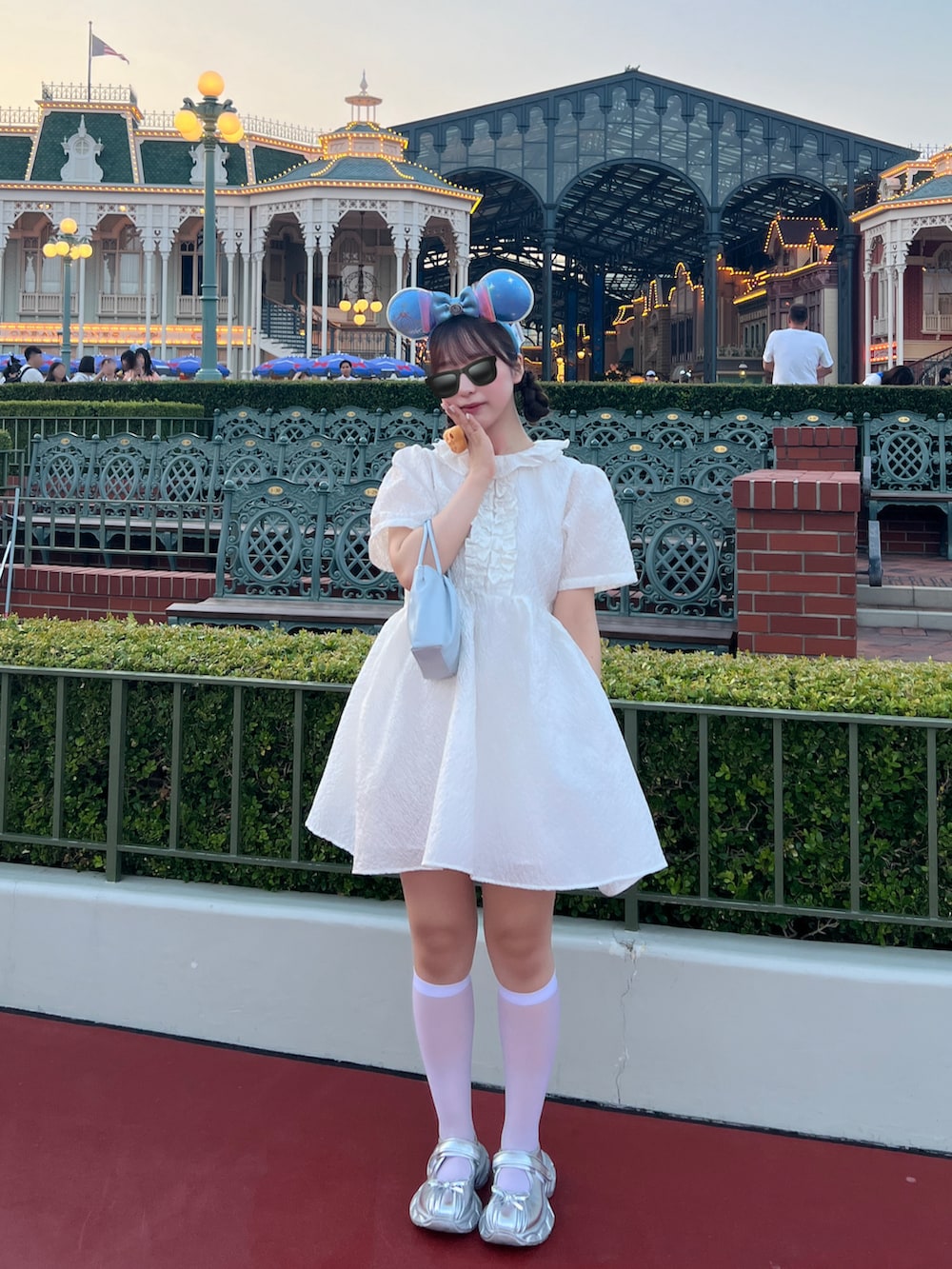 ホワイト系のワンピース、シルバー系のバレエシューズ、ブルー系のショルダーバッグを着用したレディースの夏コーディネートの3枚目の写真