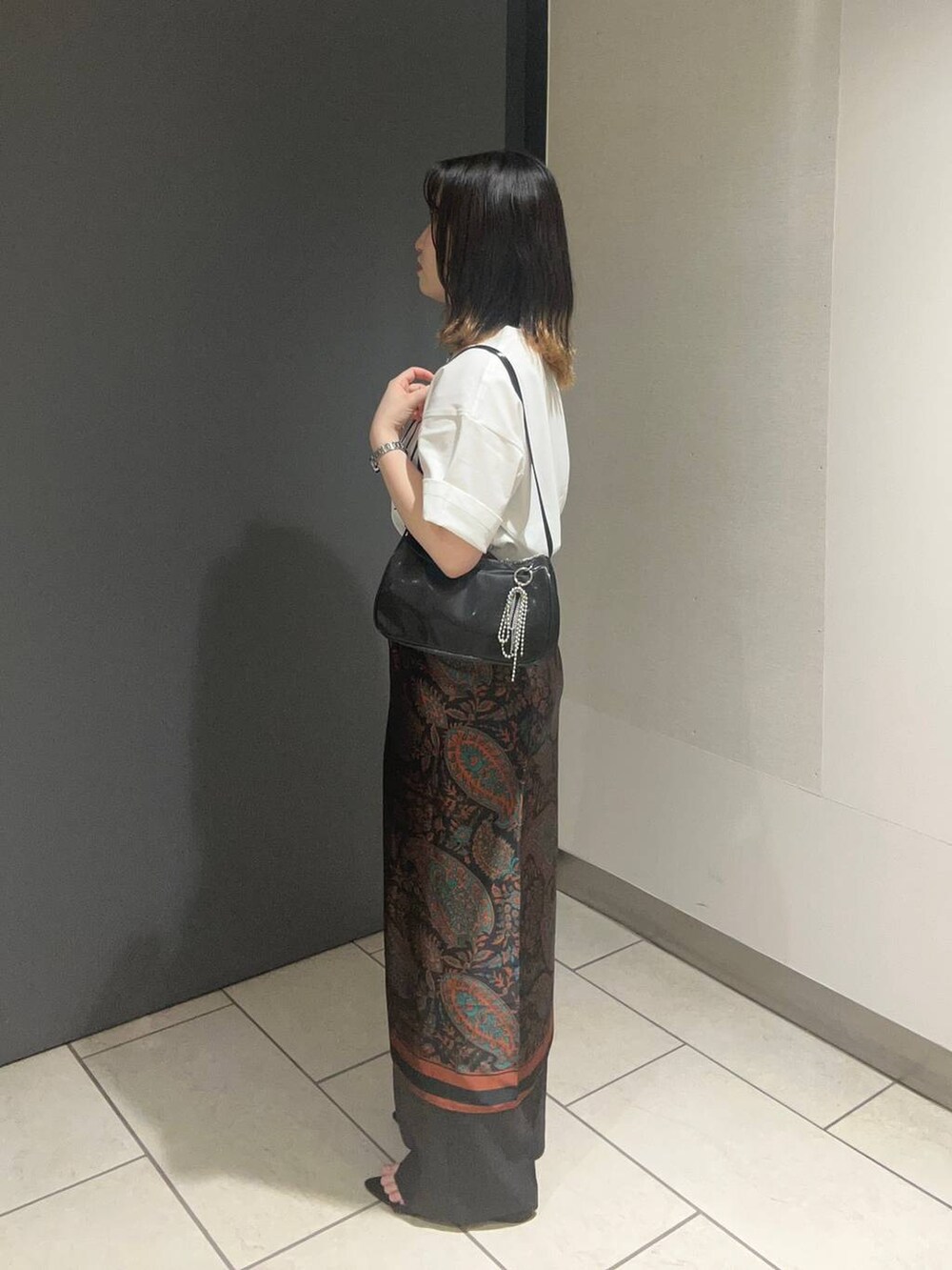 ブラック系のサンダル、ホワイト系のTシャツ/カットソー、グレー系のスラックスを着用したレディースの春コーディネートの2枚目の写真