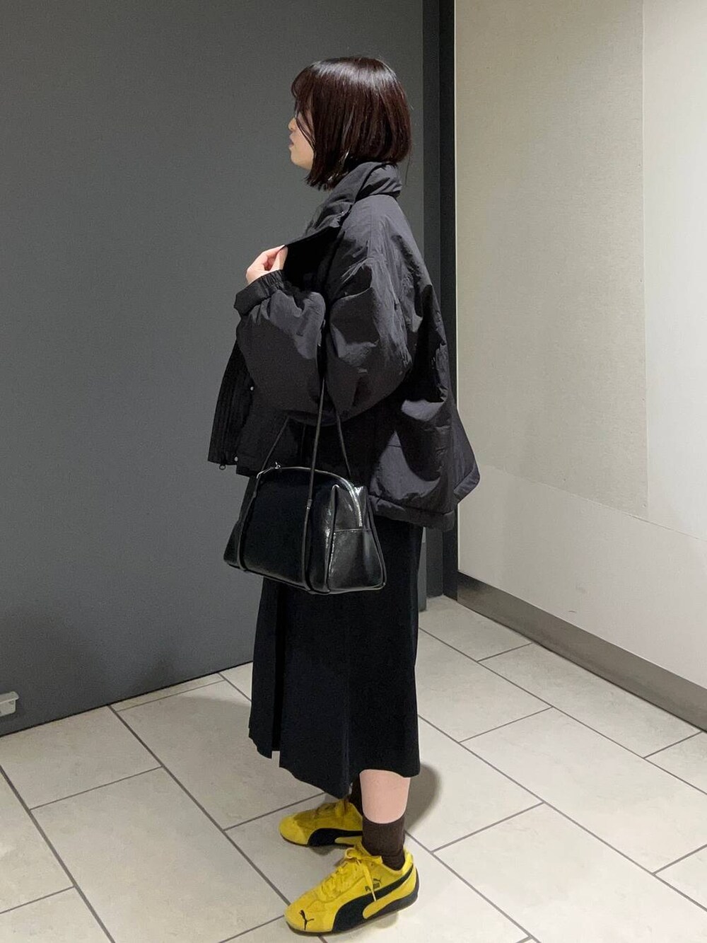 ブラック系のその他アウター、ブラック系のチノパンツ、ブラック系のボストンバッグを着用したレディースの秋コーディネートの2枚目の写真