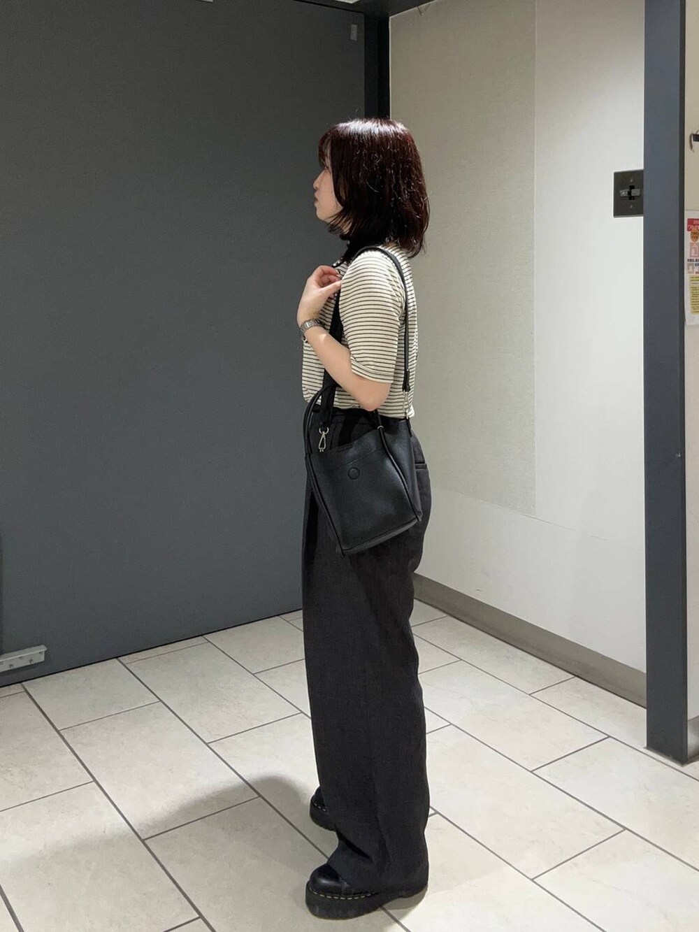 グレー系のスラックス、ブラック系のショルダーバッグ、ブラック系のTシャツ/カットソーを着用したレディースの夏コーディネートの2枚目の写真