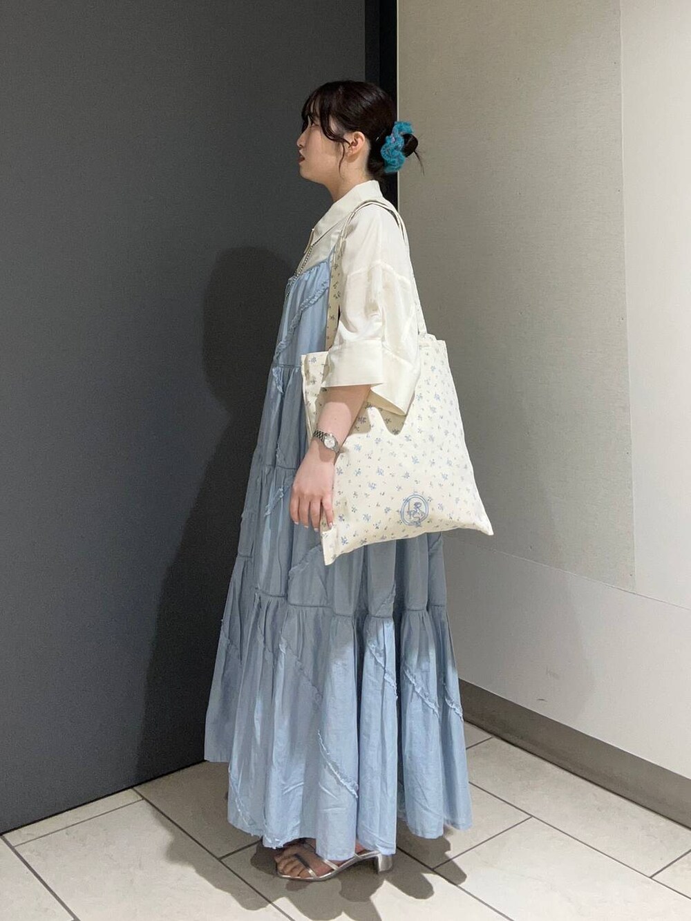 その他のトートバッグ、ブルー系のワンピース、シルバー系のサンダルを着用したレディースの夏コーディネートの2枚目の写真