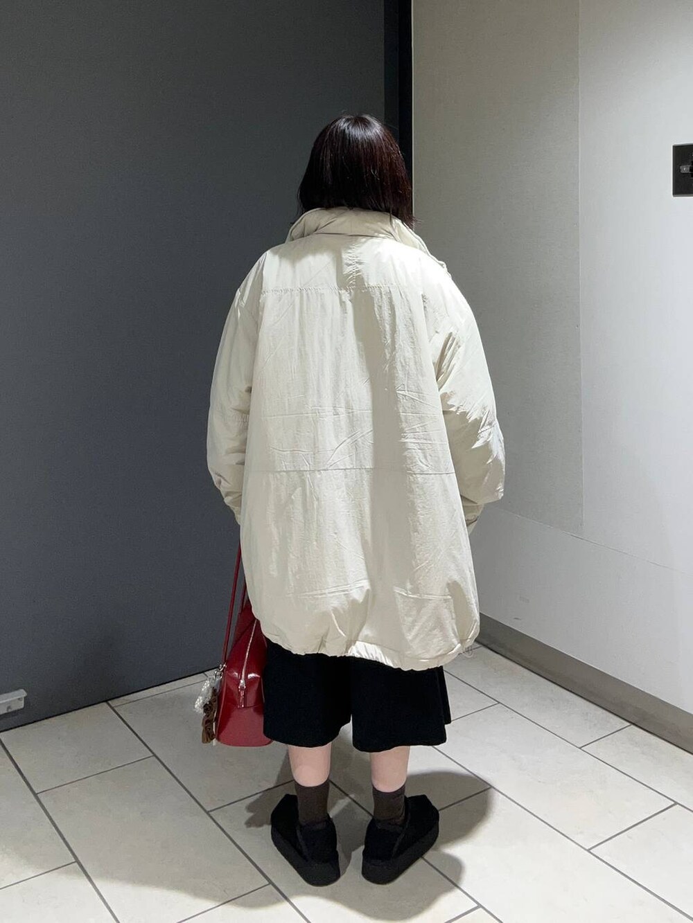 ホワイト系のブルゾン、レッド系のニット/セーター、ブラック系のチノパンツを着用したレディースの秋コーディネートの3枚目の写真