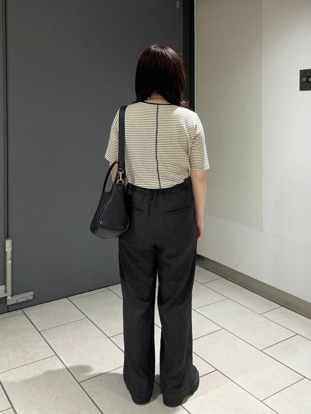 グレー系のスラックス、ブラック系のショルダーバッグ、ブラック系のTシャツ/カットソーを着用したレディースの夏コーディネートの3枚目の写真