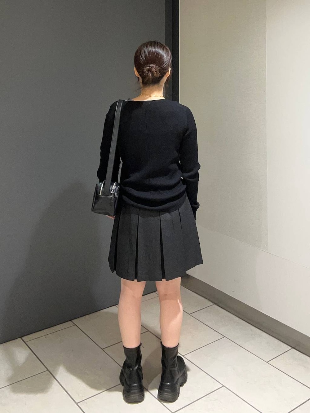 ブラック系のブーツ、グレー系のスカート、ブラック系のショルダーバッグを着用したレディースの秋コーディネートの3枚目の写真