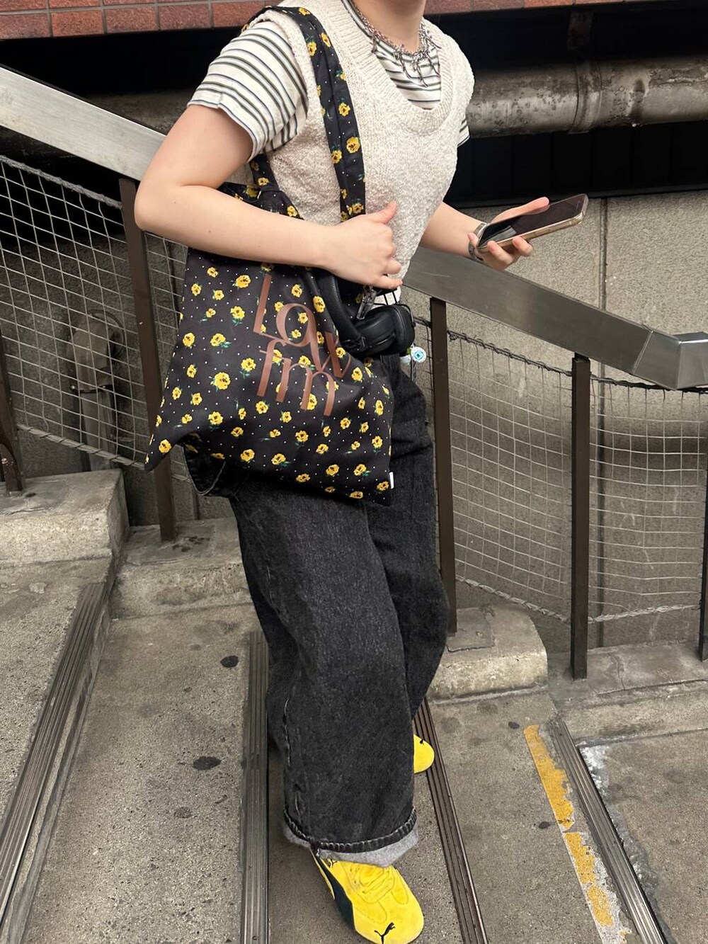 ホワイト系のTシャツ/カットソー、ブラック系のデニムパンツ、ベージュ系のニット/セーターを着用したレディースの春コーディネートの2枚目の写真