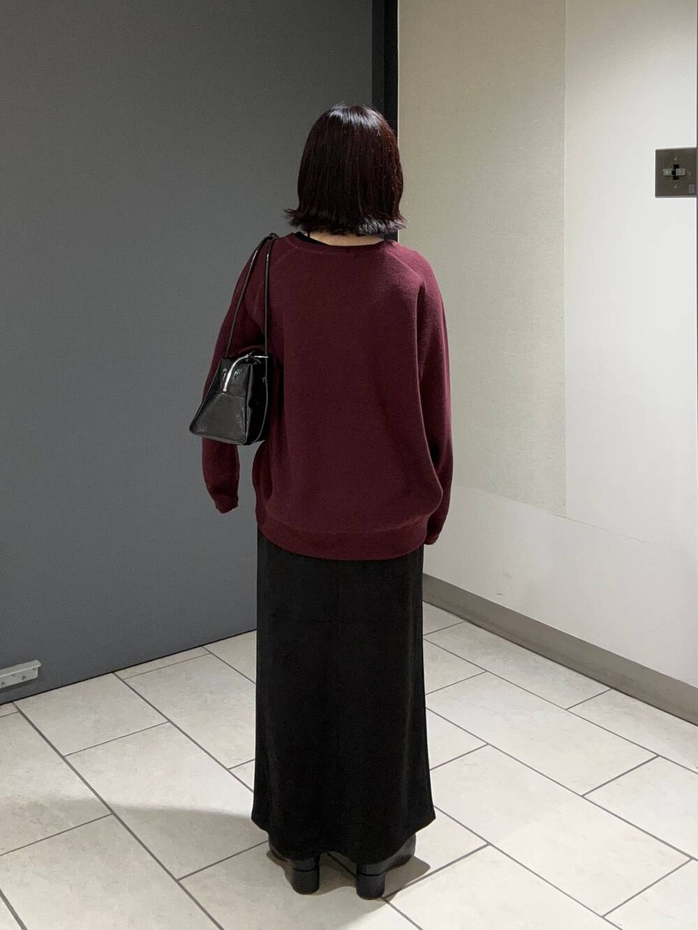 ブラック系のスカート、レッド系のニット/セーター、ブラック系のボストンバッグを着用したレディースの秋コーディネートの3枚目の写真