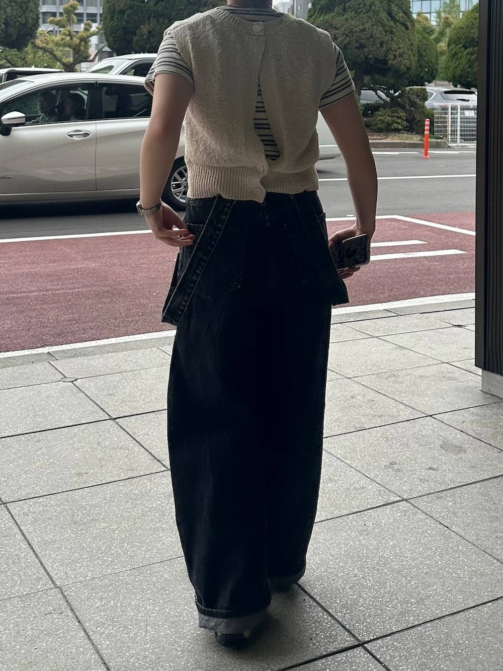 ホワイト系のTシャツ/カットソー、ブラック系のデニムパンツ、ベージュ系のニット/セーターを着用したレディースの春コーディネートの4枚目の写真