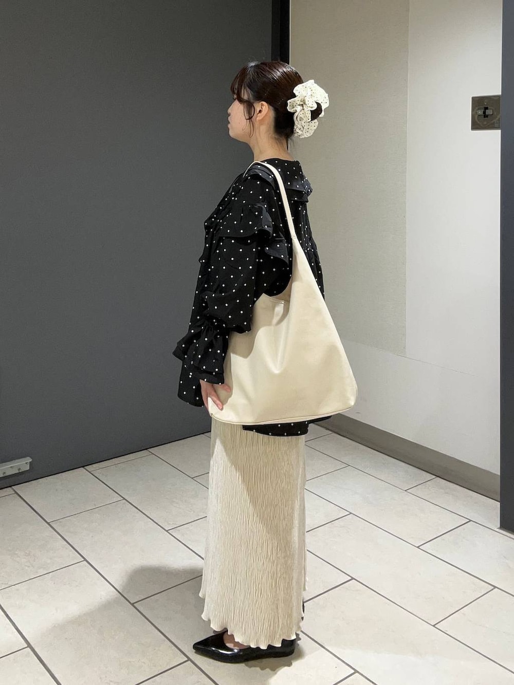 ホワイト系のショルダーバッグ、ブラック系のパンプス、ホワイト系のスカートを着用したレディースの秋コーディネートの2枚目の写真