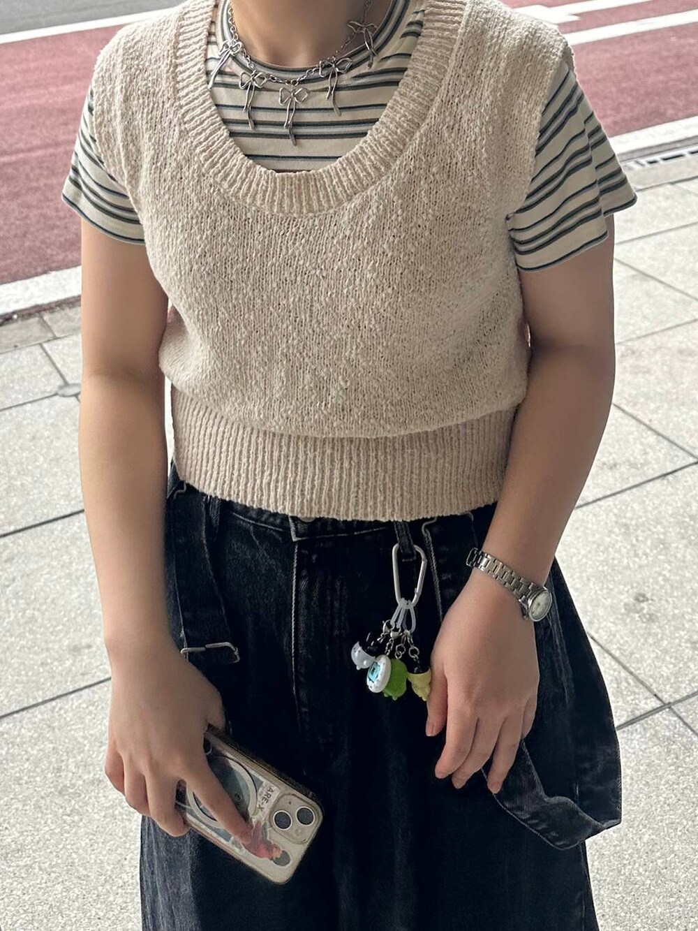 ホワイト系のTシャツ/カットソー、ブラック系のデニムパンツ、ベージュ系のニット/セーターを着用したレディースの春コーディネートの6枚目の写真