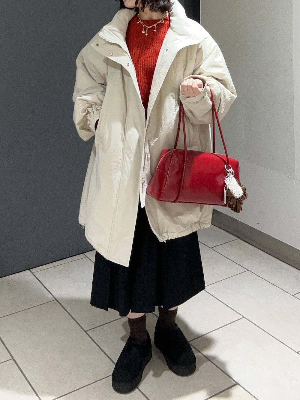 ホワイト系のブルゾン、レッド系のニット/セーター、ブラック系のチノパンツを着用したレディースの秋コーディネートの4枚目の写真
