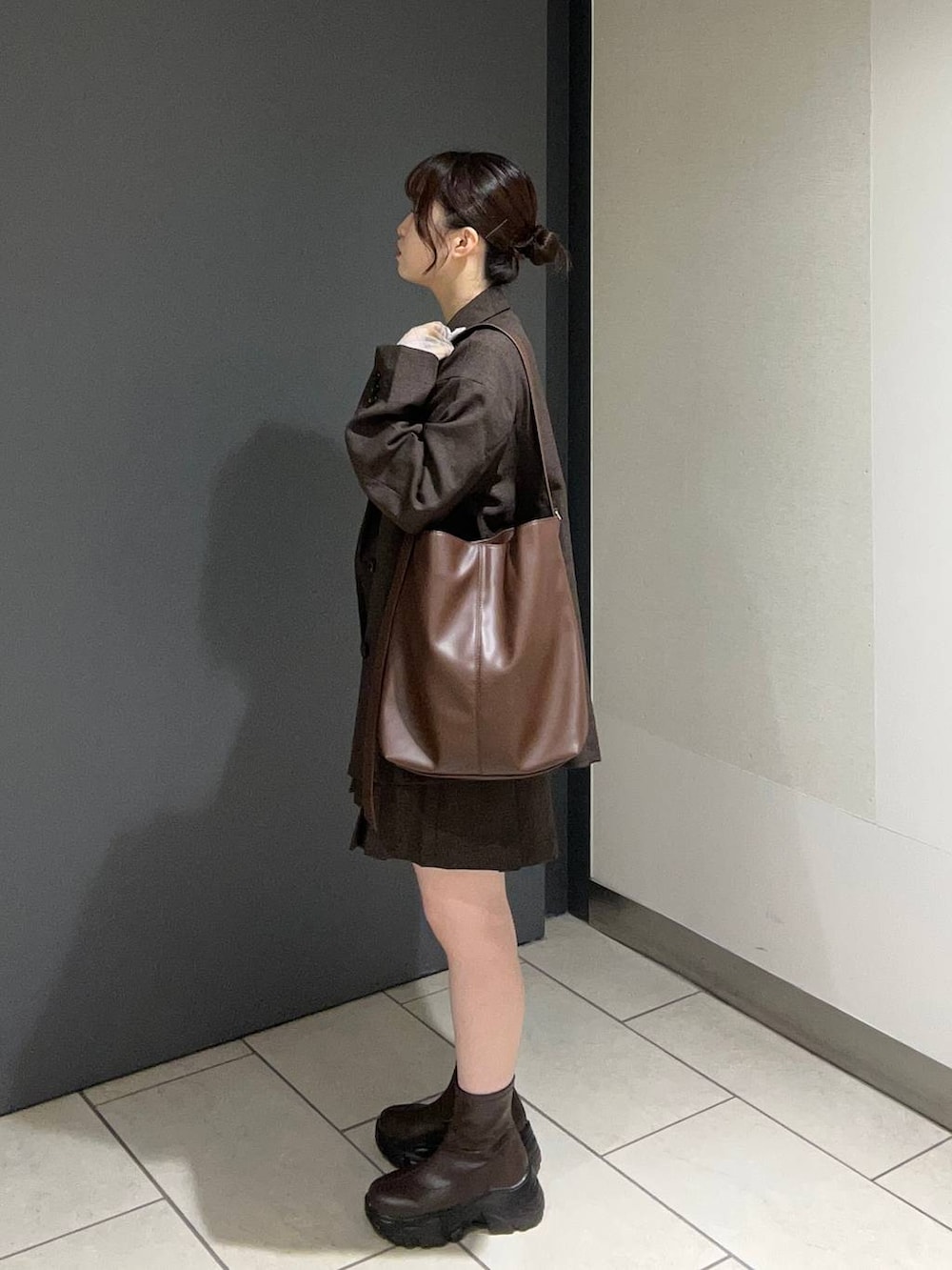 ブラウン系のテーラードジャケット、ブラウン系のスカート、ブラウン系のショルダーバッグを着用したレディースの秋コーディネートの2枚目の写真