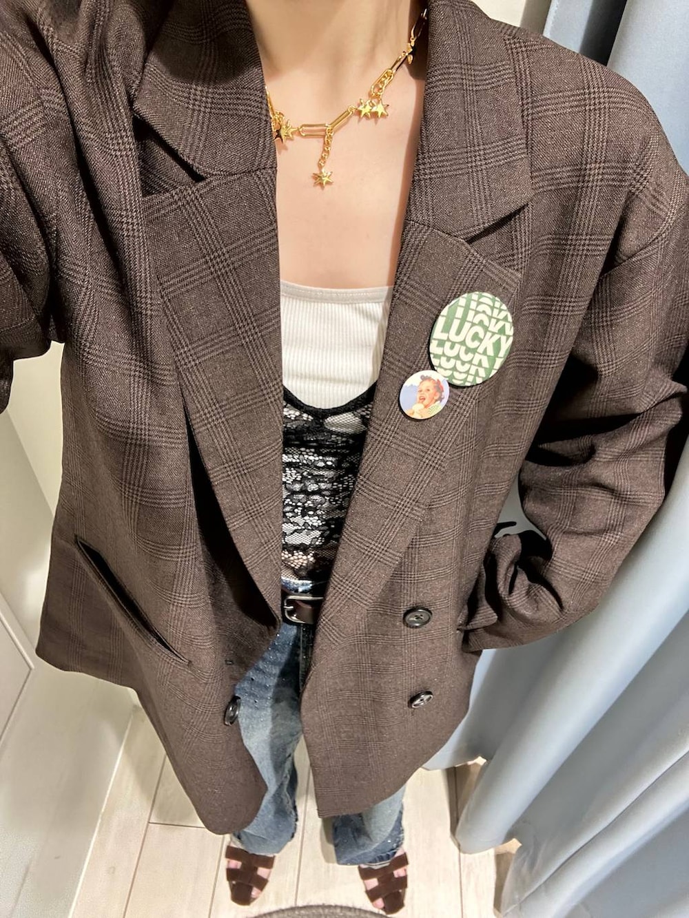 ブルー系のデニムパンツ、ブラウン系のテーラードジャケット、ブラウン系のサンダルを着用したレディースの秋コーディネートの3枚目の写真