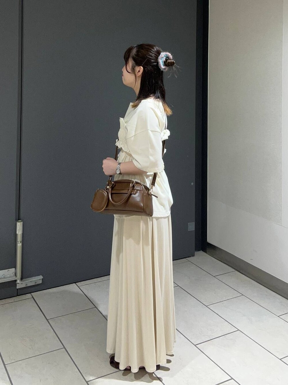 ブラウン系のサンダル、ブラウン系のショルダーバッグ、ホワイト系のスカートを着用したレディースの夏コーディネートの2枚目の写真