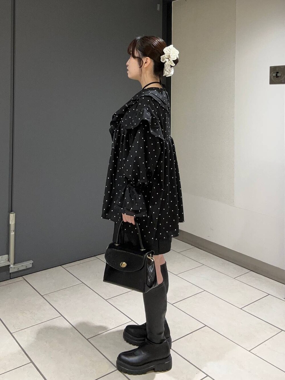 グレー系のスカート、ブラック系のボストンバッグ、ブラック系のブーツを着用したレディースの秋コーディネートの2枚目の写真