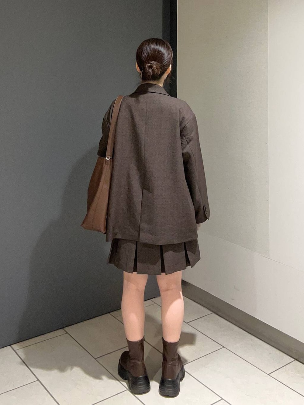 ブラウン系のテーラードジャケット、ブラウン系のスカート、ブラウン系のショルダーバッグを着用したレディースの秋コーディネートの3枚目の写真
