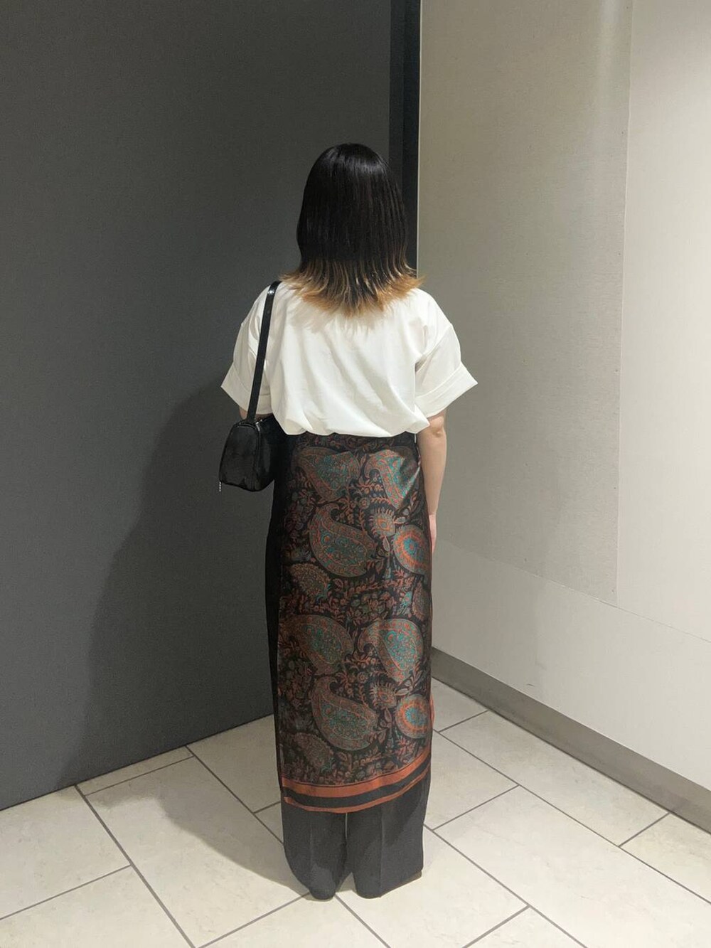 ブラック系のサンダル、ホワイト系のTシャツ/カットソー、グレー系のスラックスを着用したレディースの春コーディネートの3枚目の写真