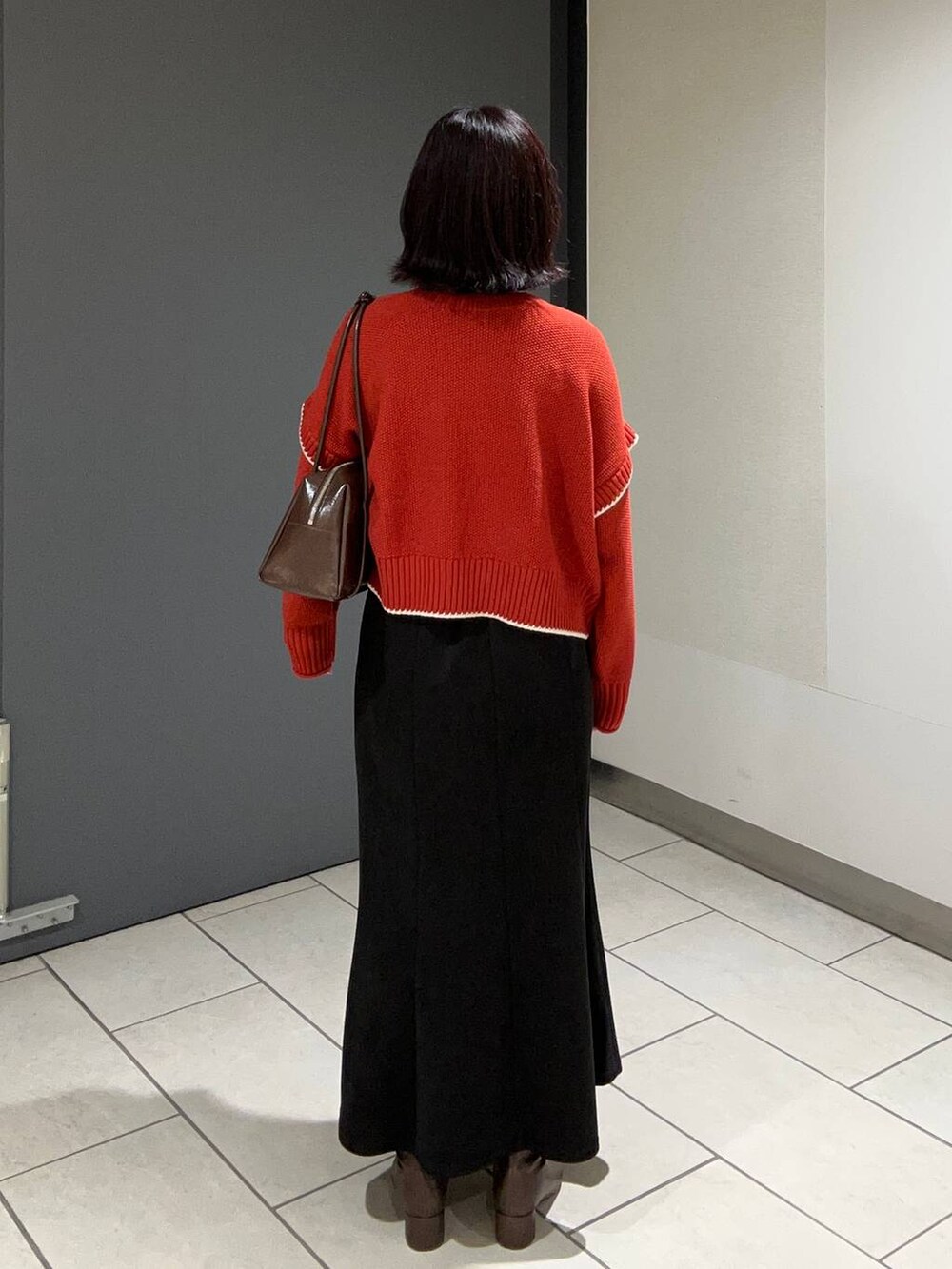 レッド系のニット/セーター、ブラック系のスカート、ブラウン系のボストンバッグを着用したレディースの秋コーディネートの3枚目の写真