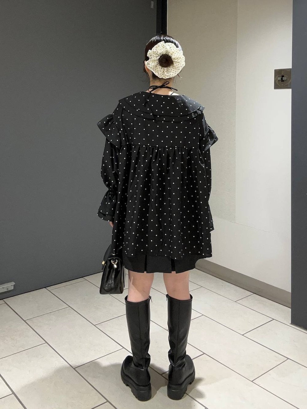 グレー系のスカート、ブラック系のボストンバッグ、ブラック系のブーツを着用したレディースの秋コーディネートの3枚目の写真