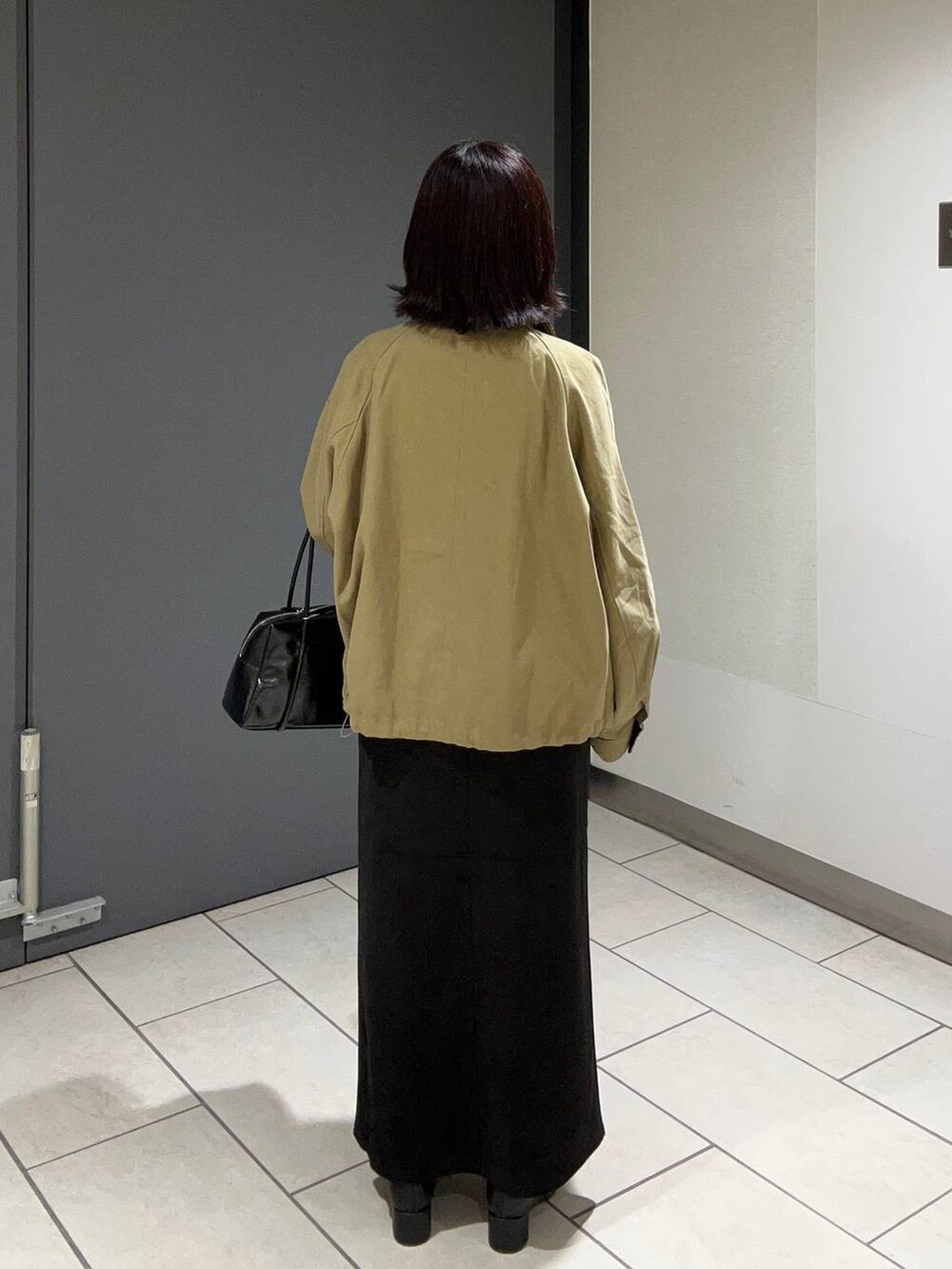 ブラウン系のその他アウター、ブラック系のスカート、ブラック系のブーツを着用したレディースの秋コーディネートの3枚目の写真