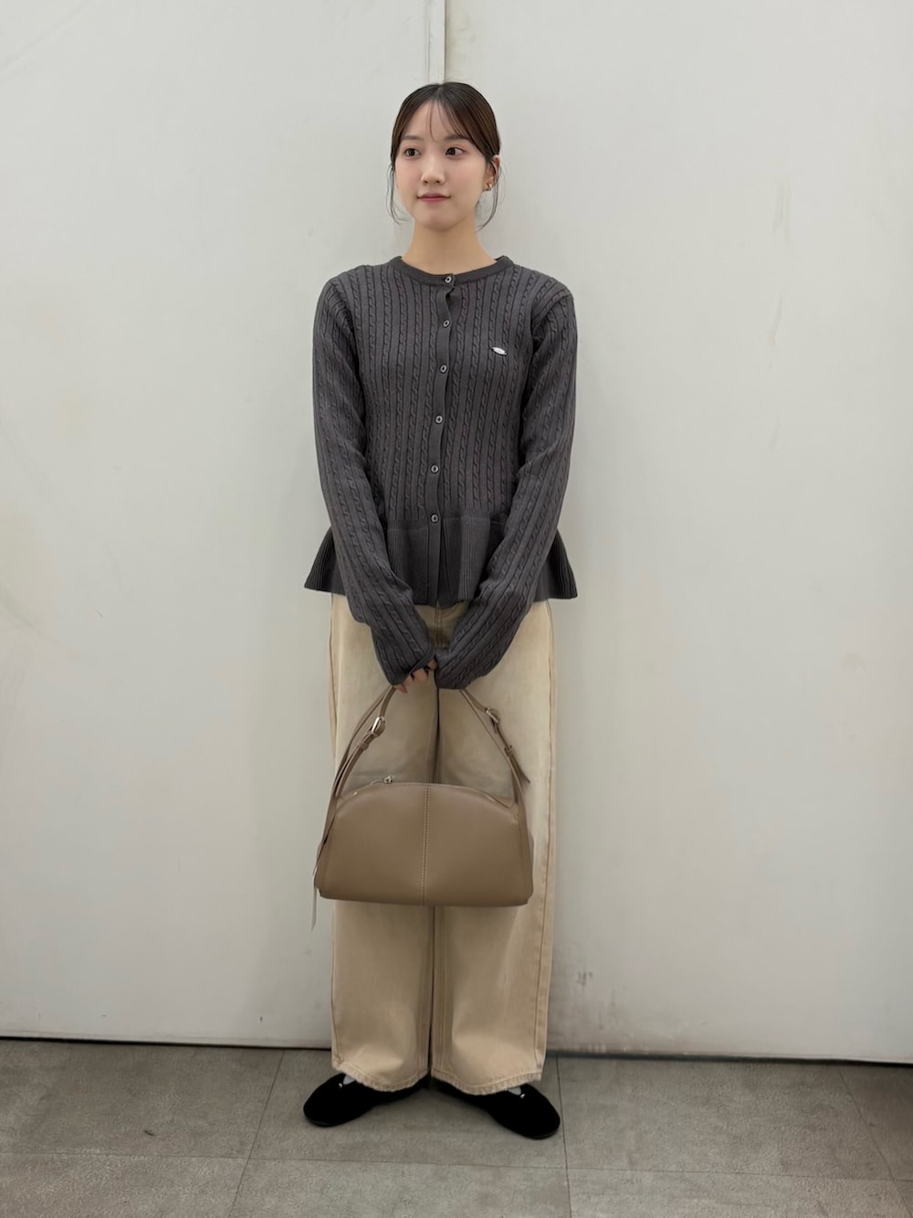 ベージュ系のデニムパンツ、ベージュ系のボストンバッグ、グリーン系のニット/セーターを着用したレディースの冬コーディネートの2枚目の写真