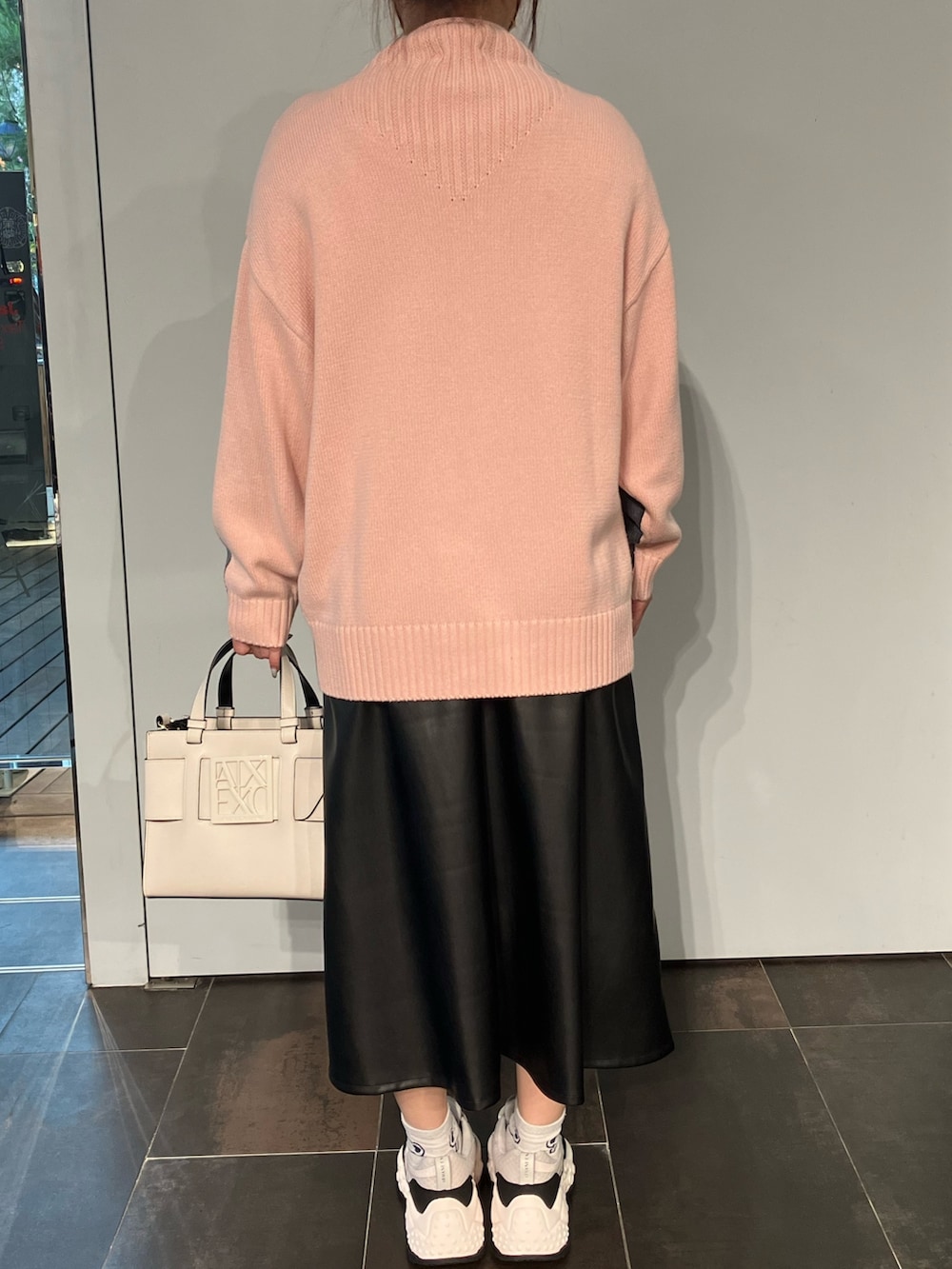 ピンク系のニット/セーター、ベージュ系のハンドバッグ、ブラック系のスカートを着用したレディースの夏コーディネートの2枚目の写真