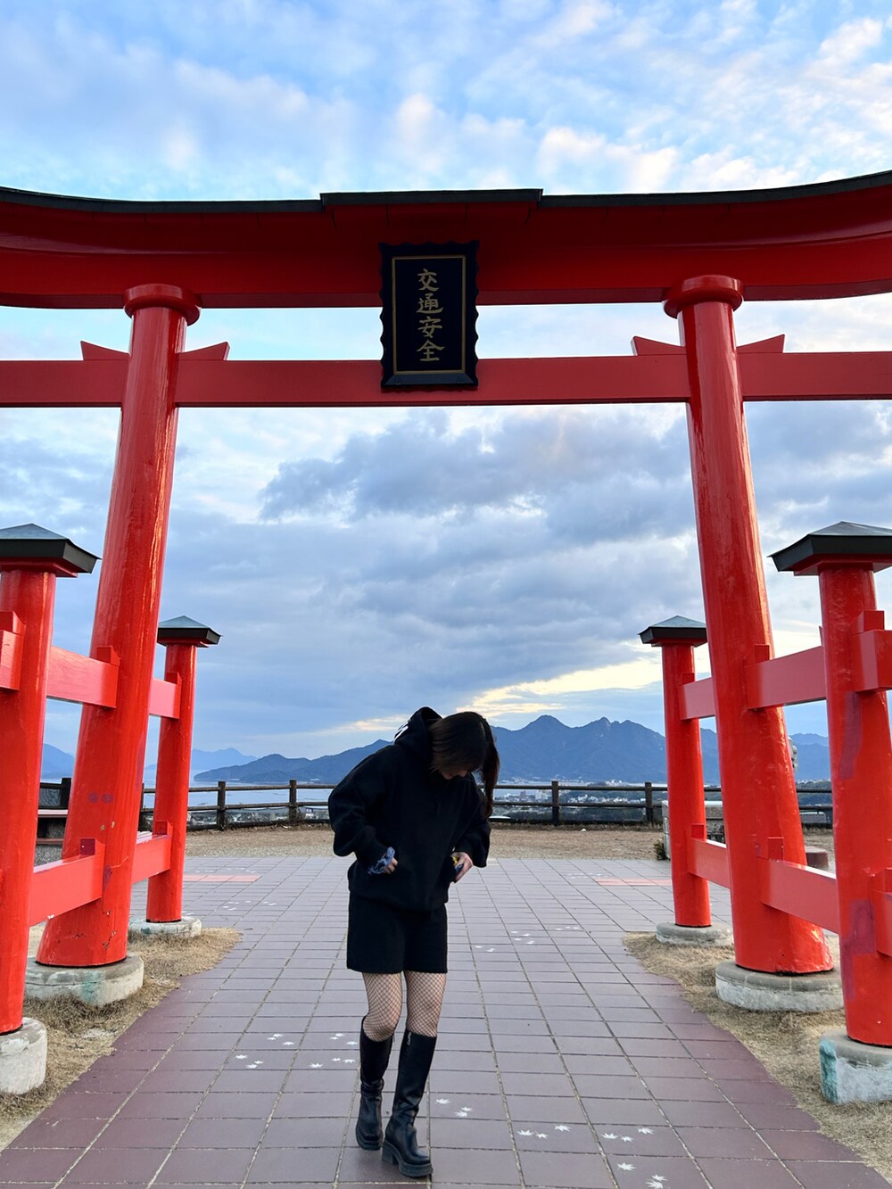 シルバー系のショルダーバッグ、ブラック系のワンピース、ブラック系のパーカーを着用したレディースの冬コーディネートの2枚目の写真