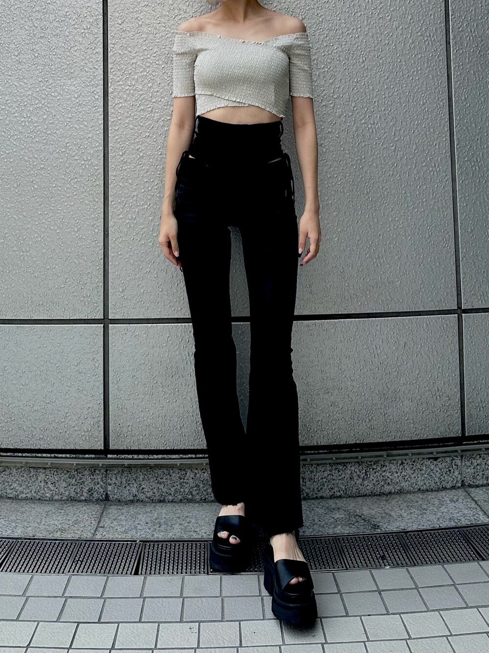 ブラック系のデニムパンツ、ベージュ系のTシャツ/カットソー、ブラック系のサンダルを着用したレディースの夏コーディネートの2枚目の写真