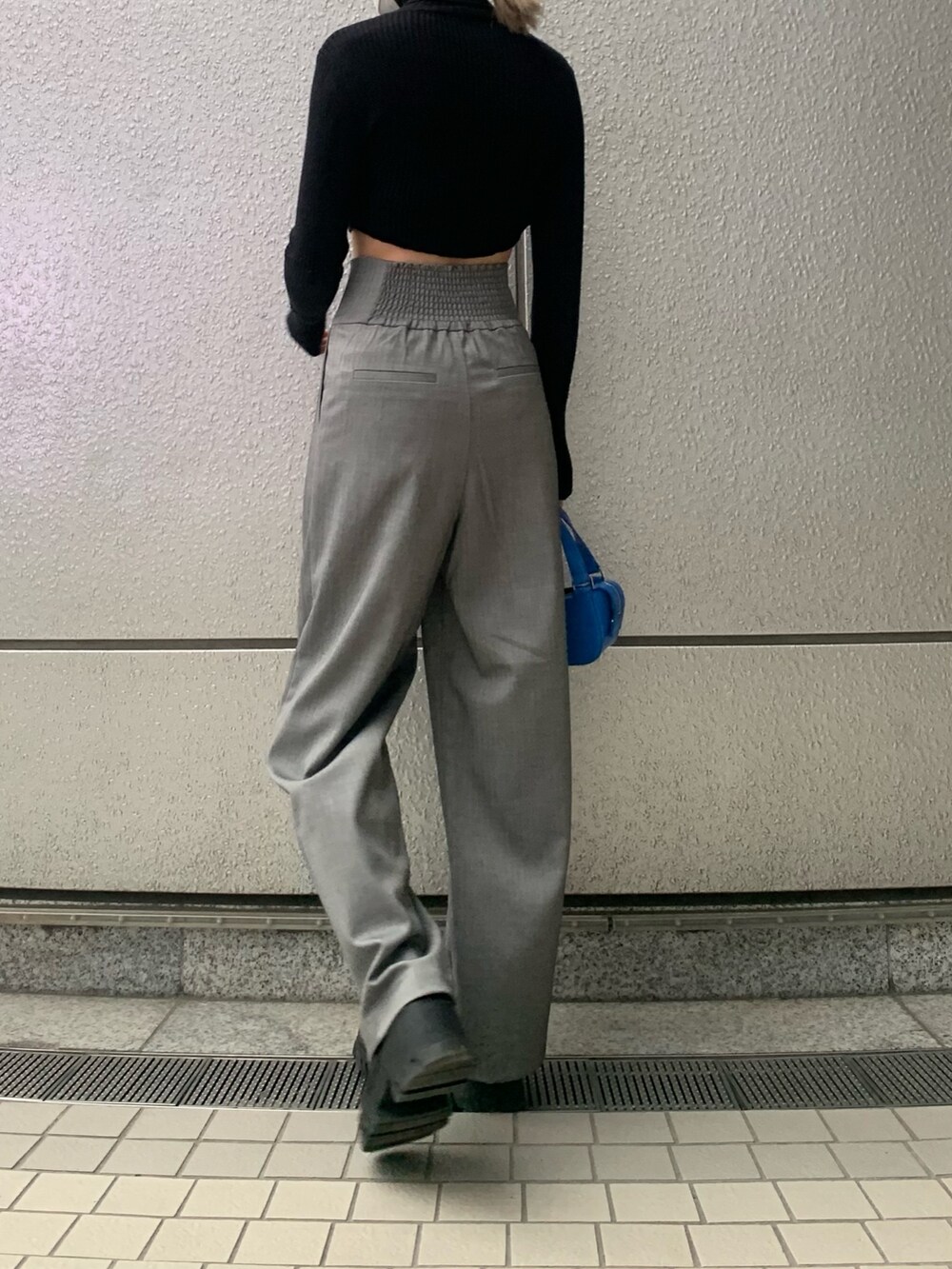 ブラック系のニット/セーター、グレー系のその他パンツ、ブルー系のハンドバッグを着用したレディースの冬コーディネートの3枚目の写真