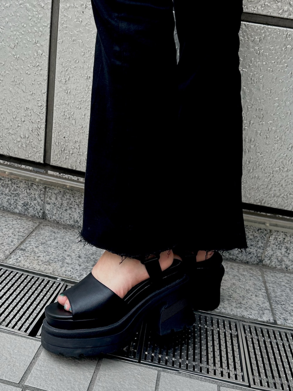 ブラック系のデニムパンツ、ベージュ系のTシャツ/カットソー、ブラック系のサンダルを着用したレディースの夏コーディネートの5枚目の写真