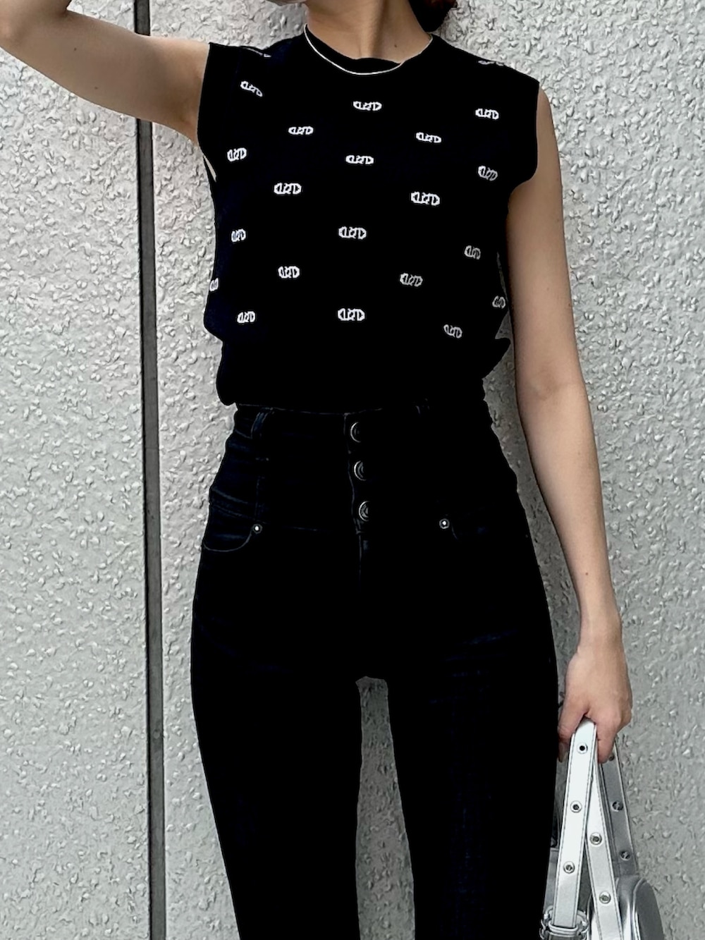 ブラック系のニット/セーター、シルバー系のショルダーバッグ、ブラック系のデニムパンツを着用したレディースの春コーディネートの3枚目の写真